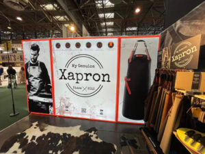 Large modular SEG light box display at trade show featuring Xapron brand with backlit graphics and product showcase