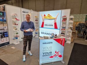 Portable trade show display booth with backlit SEG light box and modular shelving showcasing sneaker products