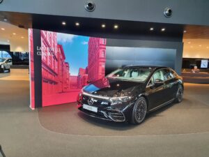 Large format SEG light box display backdrop in automotive showroom featuring vehicle and branded graphics